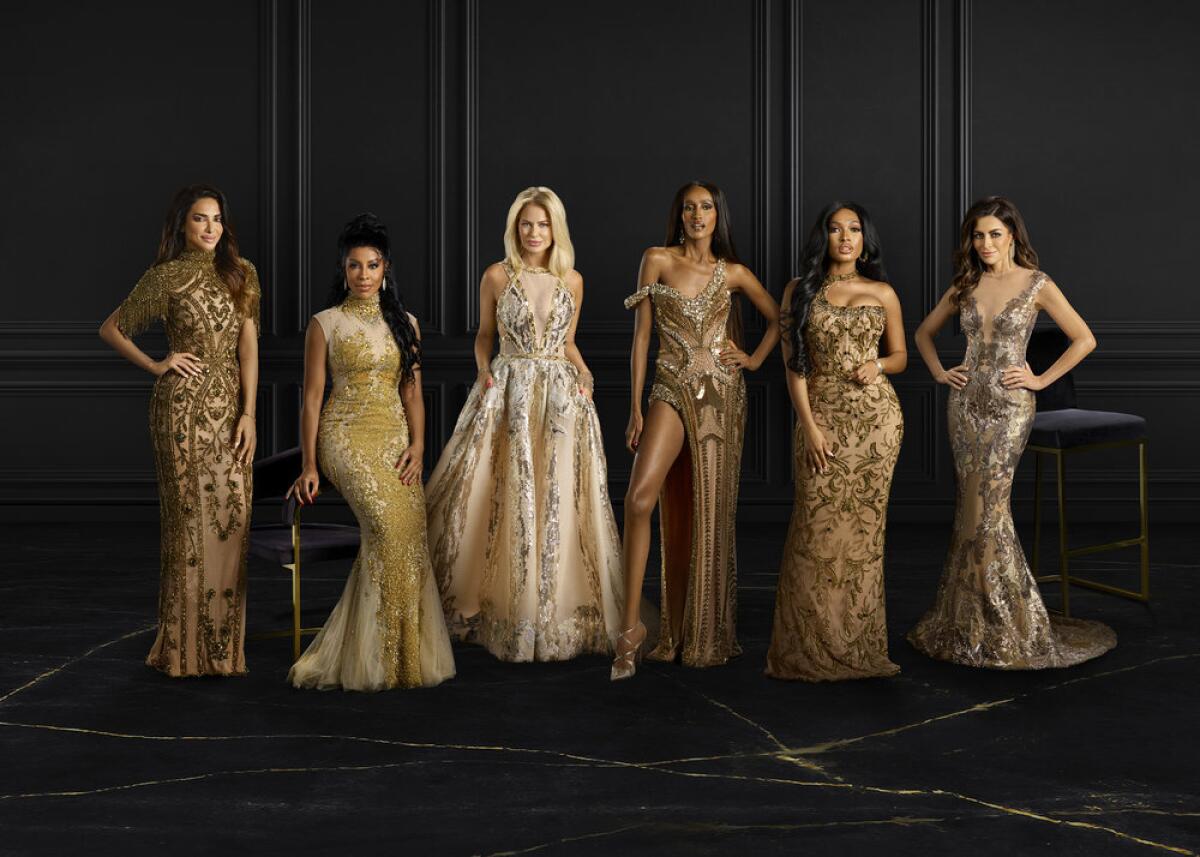 Six women posing in glamorous gold evening gowns.