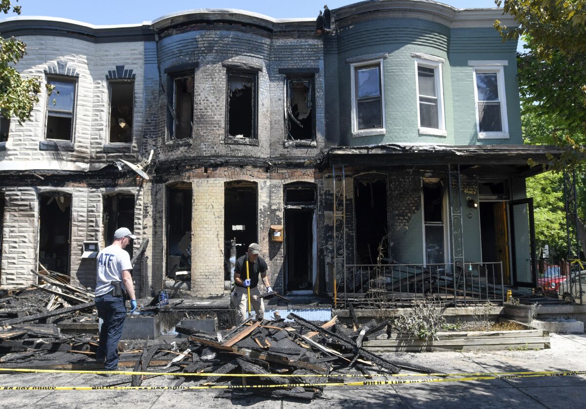 Fire investigators work at the scene of a row house fire in Baltimore, Wednesday, June 15, 2022. The fire tore through four Baltimore row homes early Wednesday, sending three people to a hospital, officials said. (AP Photo/Steve Ruark)