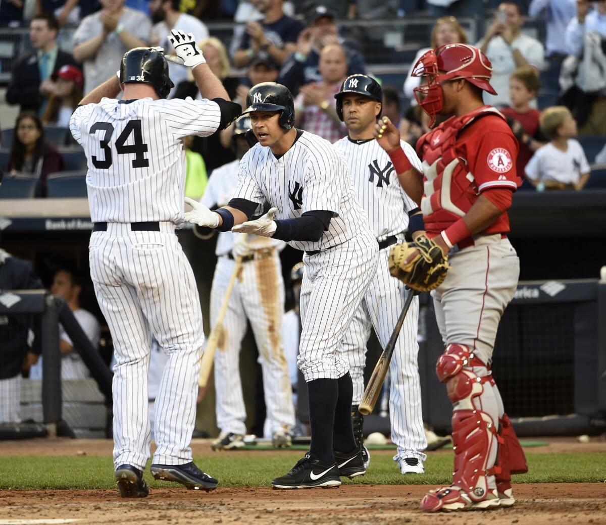 Angels catcher Carlos Perez watches as Yankees' Alex Rodriguez, center, and Carlos Beltran congratulate Brian McCann, who hit a two-run home run in the first inning Saturday in New York.