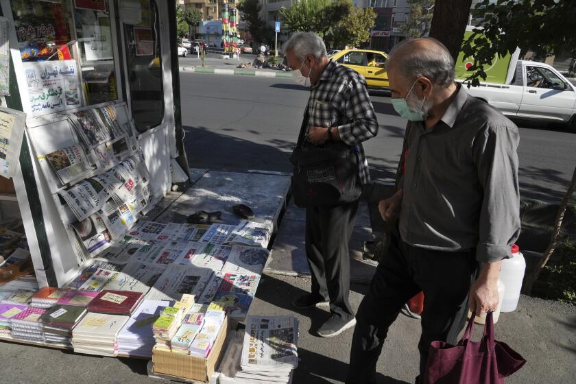 Pedestrians pause at a news stand in Tehran on Saturday.