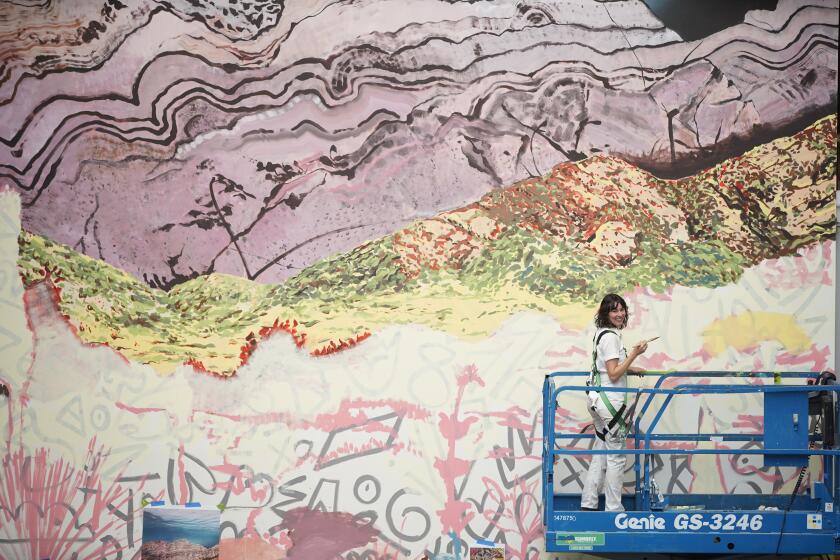 San Diego, California - October 06: On the lift Eva Struble a San Diego-based artist commissioned by The Natural History Museum works on a 30-foot mural in the Museum's atrium in Balboa Park on Friday, Oct. 6, 2023 in San Diego, California. (Alejandro Tamayo / The San Diego Union-Tribune