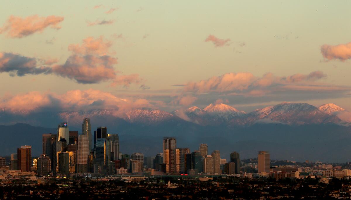 The snow-covered San Gabriel Mountains provide a dramatic backdrop to the downtown Los Angeles skyline. 