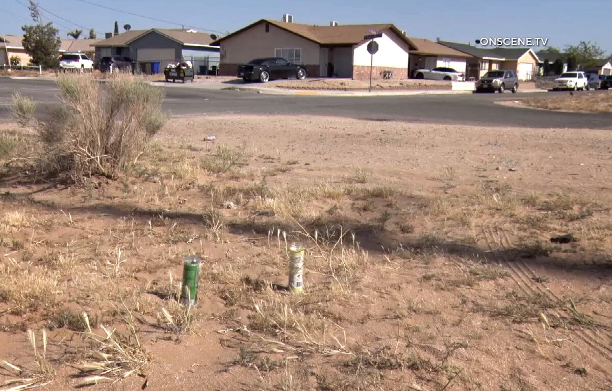 Two prayer candles in a dirt lot with homes in the background across the street