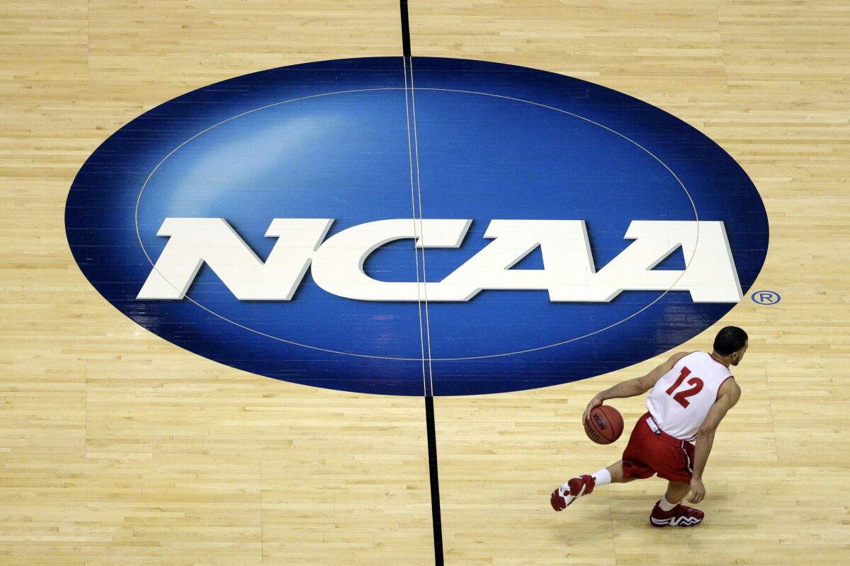 In this March 26, 2014, file photo, Wisconsin's Traevon Jackson dribbles past the NCAA logo during practice at the NCAA men's college basketball tournament. On Wednesday, the NCAA moved closer to allowing athletes to monetize their name, image and license.