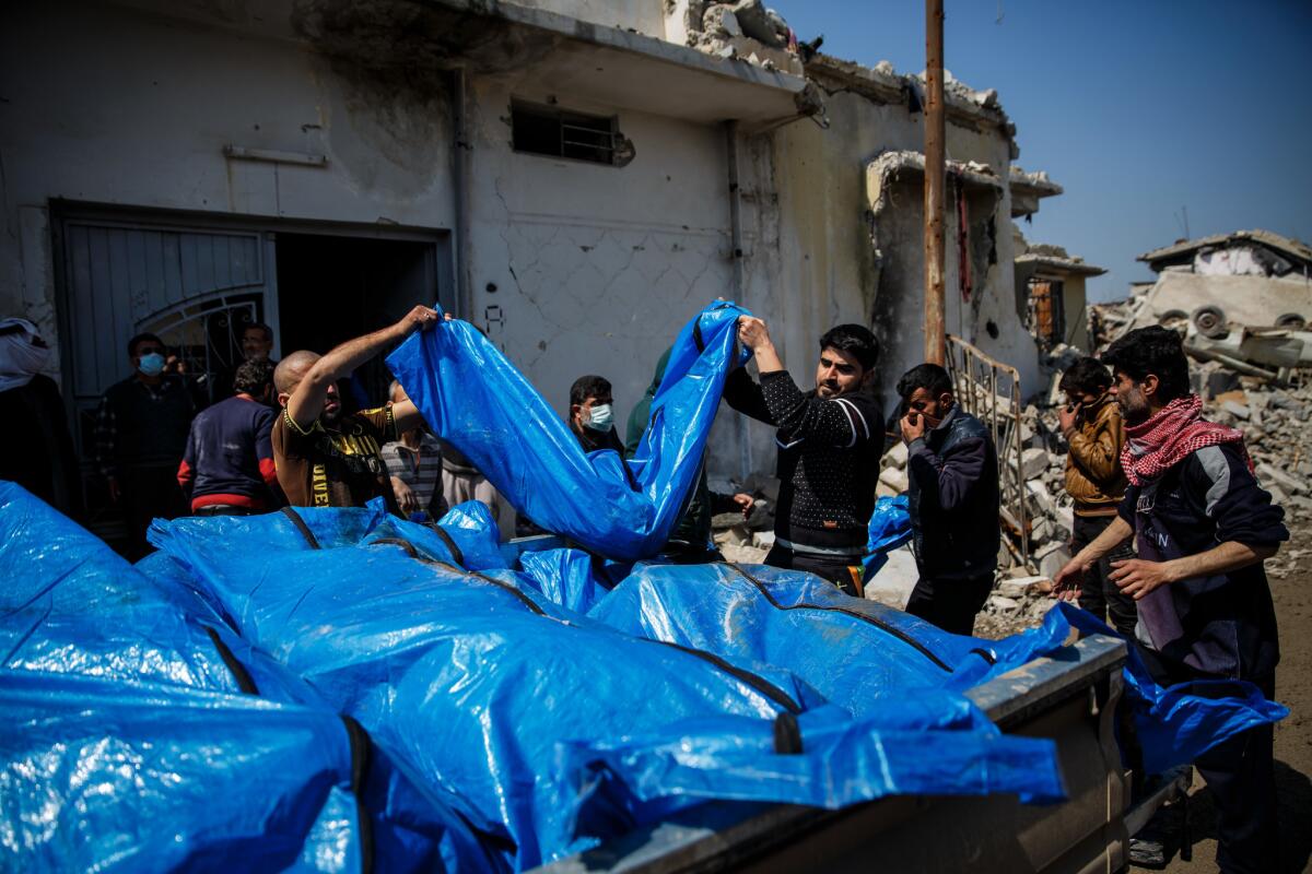 Mosul residents pile body bags in the back of a truck after recovering the dead from the rubble in Mosul.