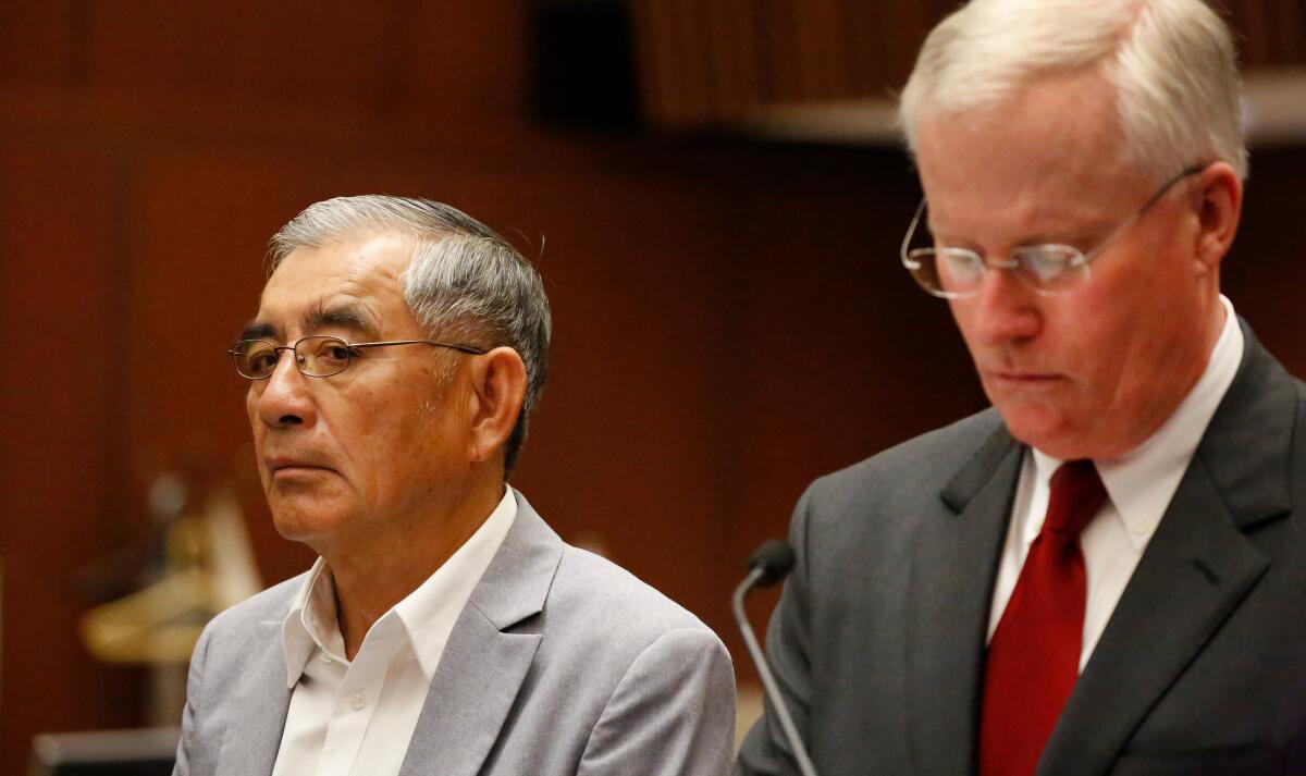 Samuel Leung, in a suit jacket, pictured from the shoulders up in a wood-paneled courtroom beside a man in a tie and jacket