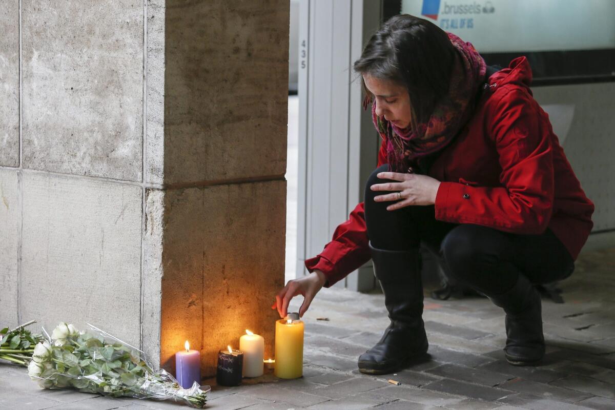 A woman lights a candle in the area of the explosion at the Maelbeek subway station in Brussels, Belgium.