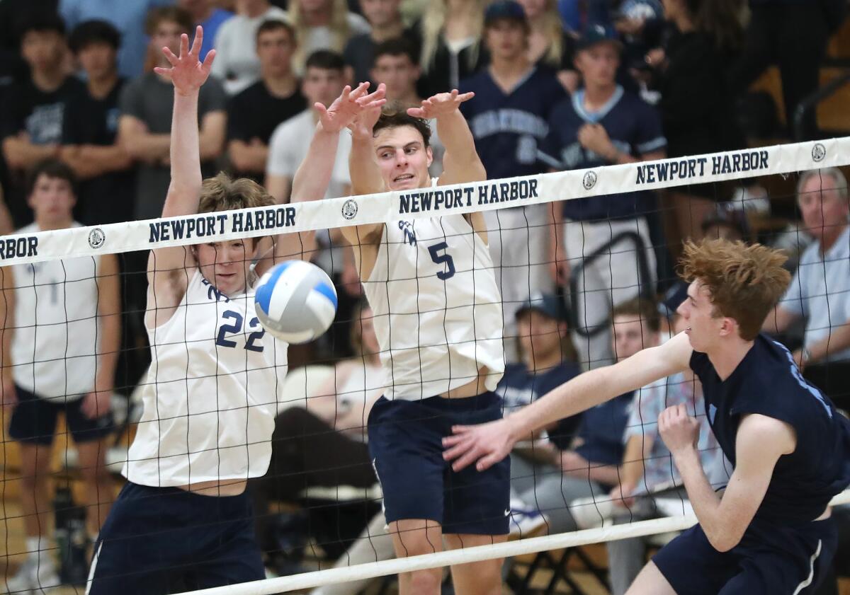 Newport Harbor's Charlie Herrington (22) and Riggs Guy (5) block a spike attempt by Corona del Mar's Brady Gant on Wednesday.