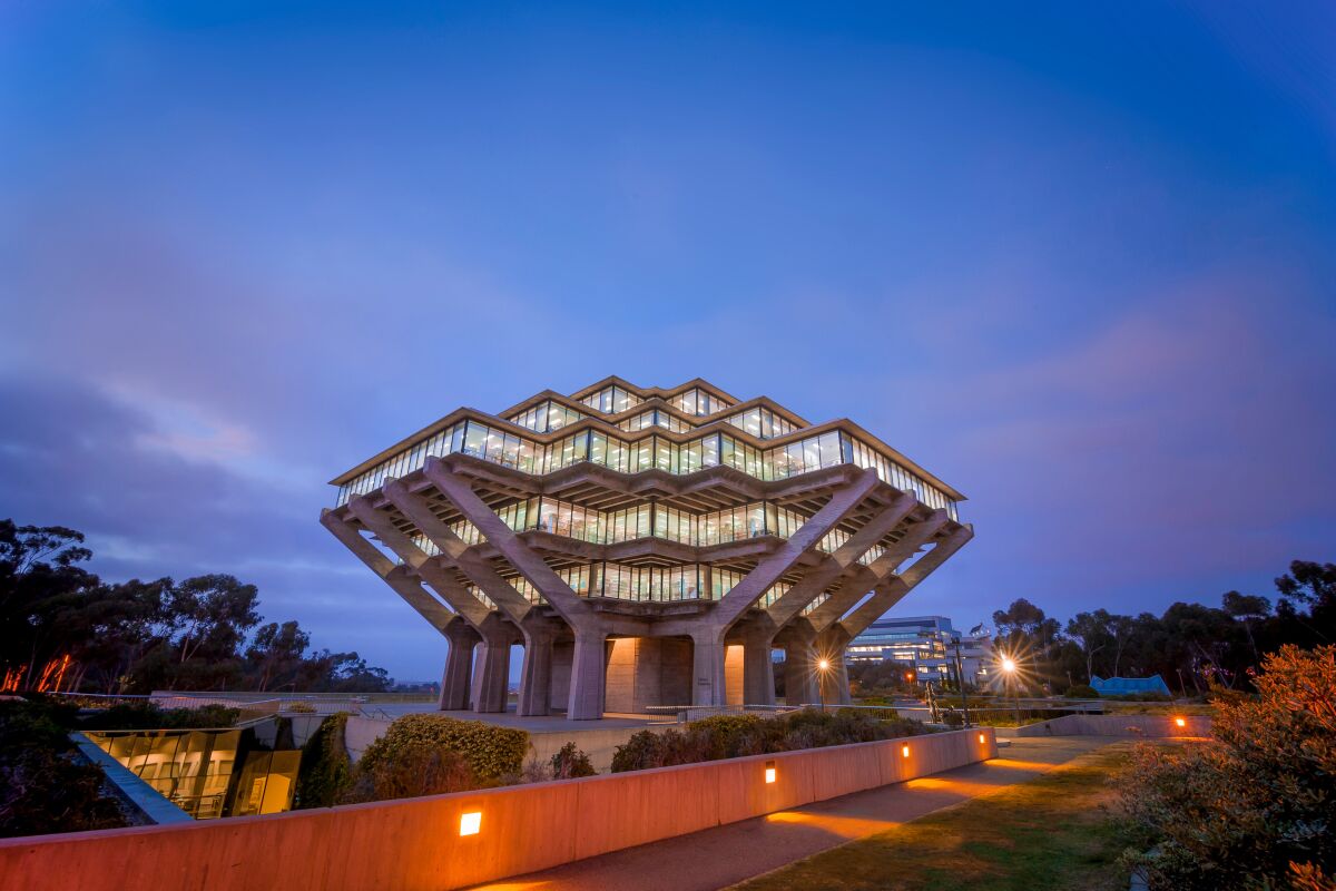 A view of the spaceship form of Geisel Library at dusk, with the building illuminated from within.
