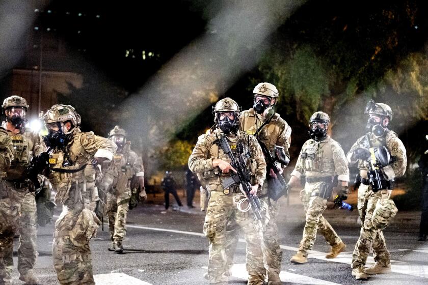 Federal agents disperse Black Lives Matter protesters near the Mark O. Hatfield United States Courthouse on Monday, July 20, 2020, in Portland, Ore. Officers used teargas and projectiles to move the crowd after some protesters tore down a fence fronting the courthouse. (AP Photo/Noah Berger)