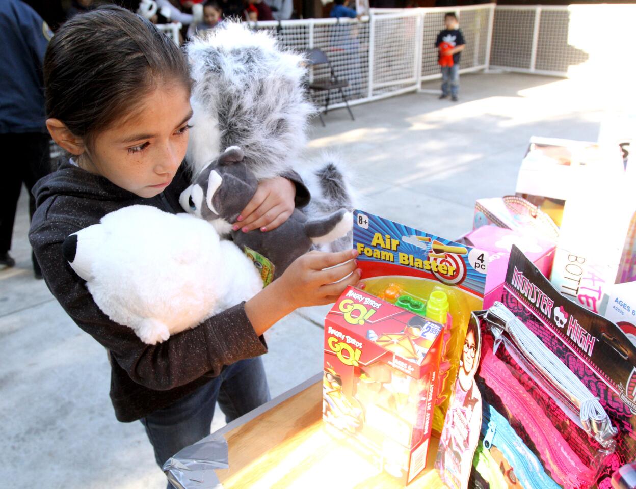 Hannah Covarrubias, 9 of Sun Valley, holds two stuffed toys as she looks for another toy she will take home with her during the Crescenta Valley Sheriff Station's annual Toy and Food Drive at Crescenta Valley Park in La Crescenta on Saturday, Dec. 19, 2015.
