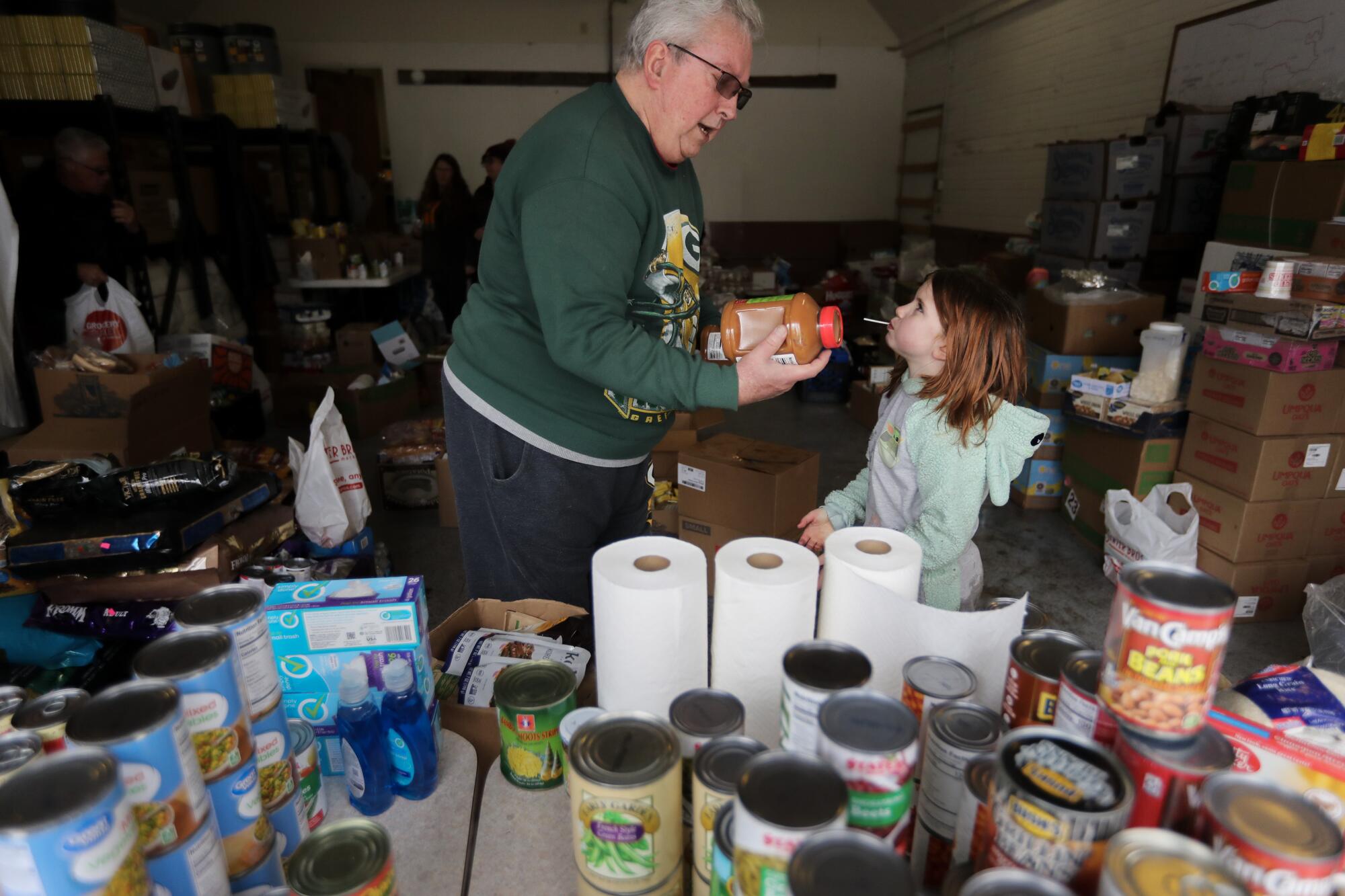 A man and a girl sort items at a food pantry. 