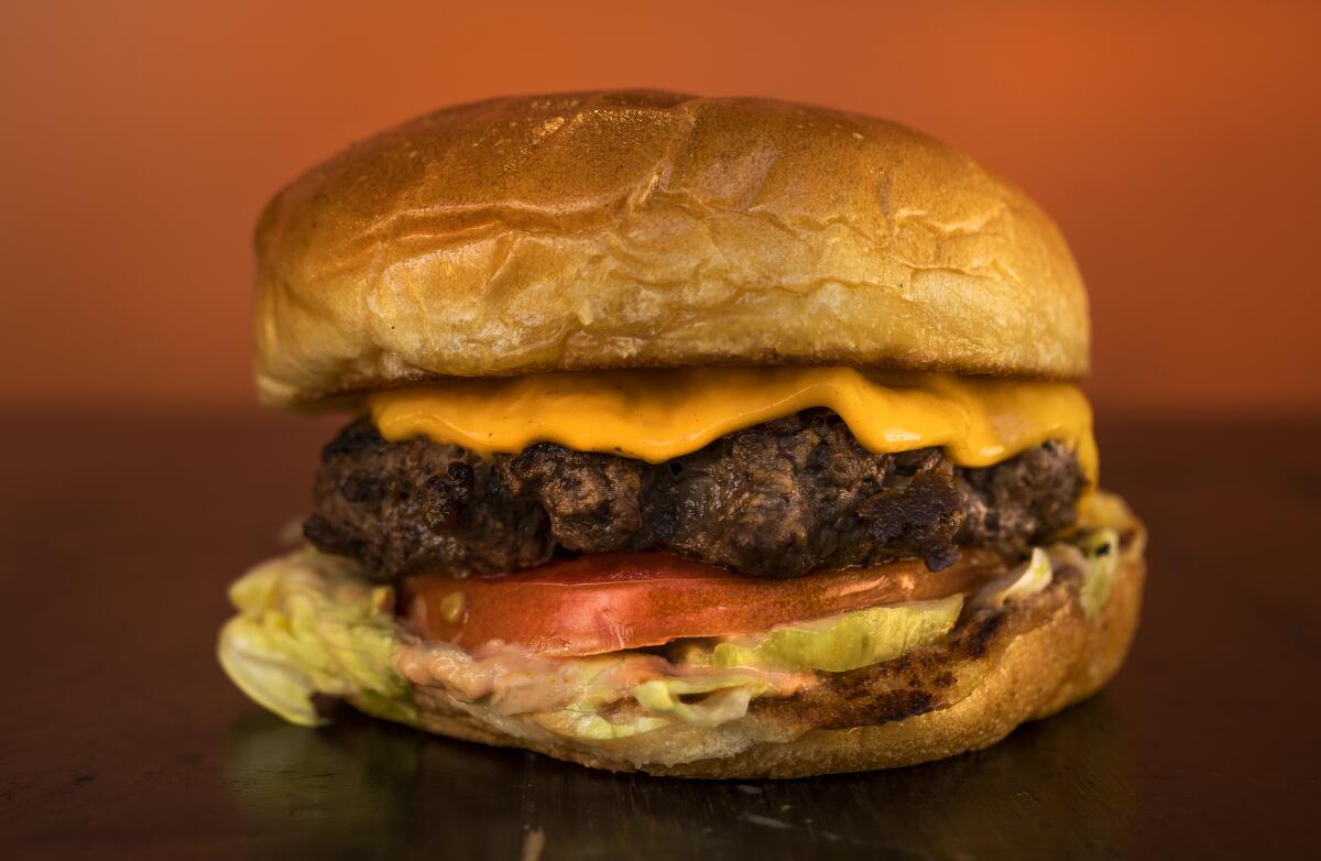 A burger topped with meat, cheese, lettuce and tomatoes