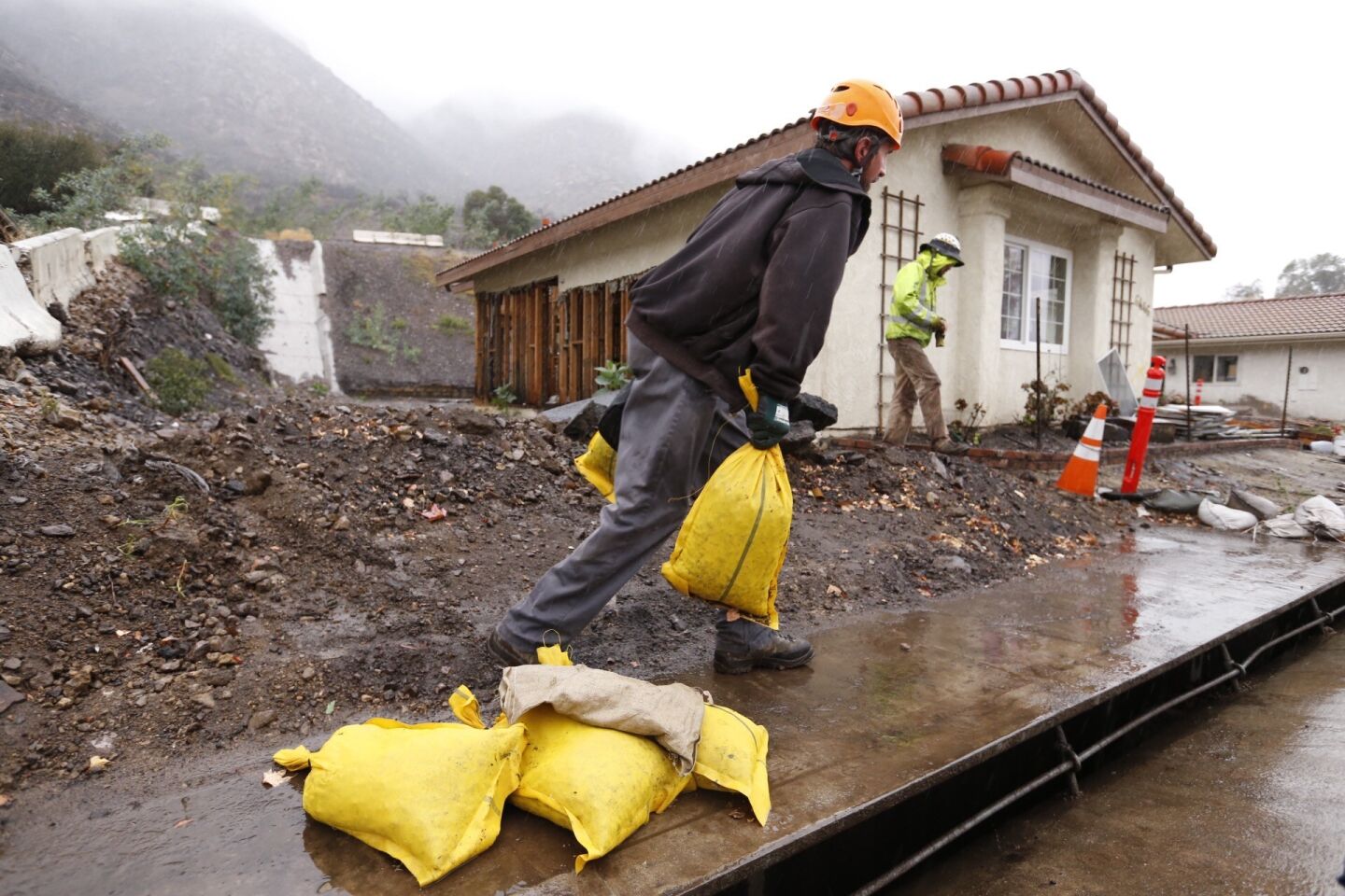 Jason Rivas works with sandbags in front of homes along San Como Lane in Camarillo Springs. Residents are under a voluntary evacuation order.