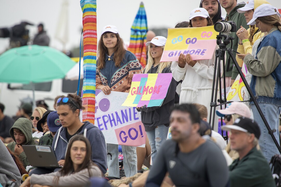  Fans of seven-time WSL champion Stephanie Gilmore of Australia hold signs while watching her match with Johanne Defay