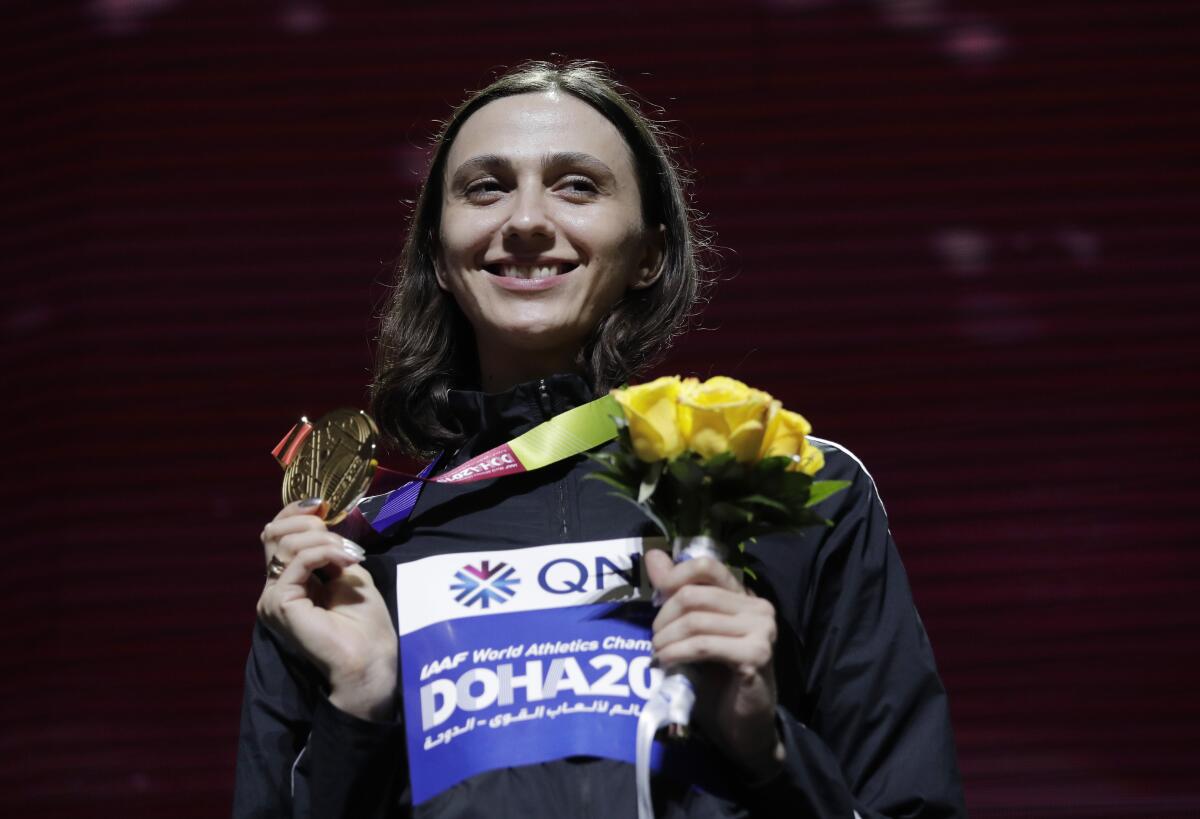 Mariya Lasitskene, who participates as a neutral athlete, poses during the medal ceremony for the women's high jump at the World Athletics Championships in Doha, Qatar on Oct. 1, 2019. Three-time world high jump champion Mariya Lasitskene has assailed Russian track leaders after they were charged with using fake medical documents during an investigation. Lasitskene has called for swift and radical reforms and the removal of officials appointed by track federation president Dmitry Shlyakhtin.