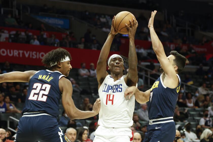 Los Angeles Clippers guard Terance Mann (14) drives between Denver Nuggets forward Zeke Nnaji (22) and Denver Nuggets gaird Facundo Campazzo (7) during the second half of a preseason NBA basketball game, Monday, Oct. 4, 2021, in Los Angeles. The Clippers won 103-102. (AP Photo/Ringo H.W. Chiu)