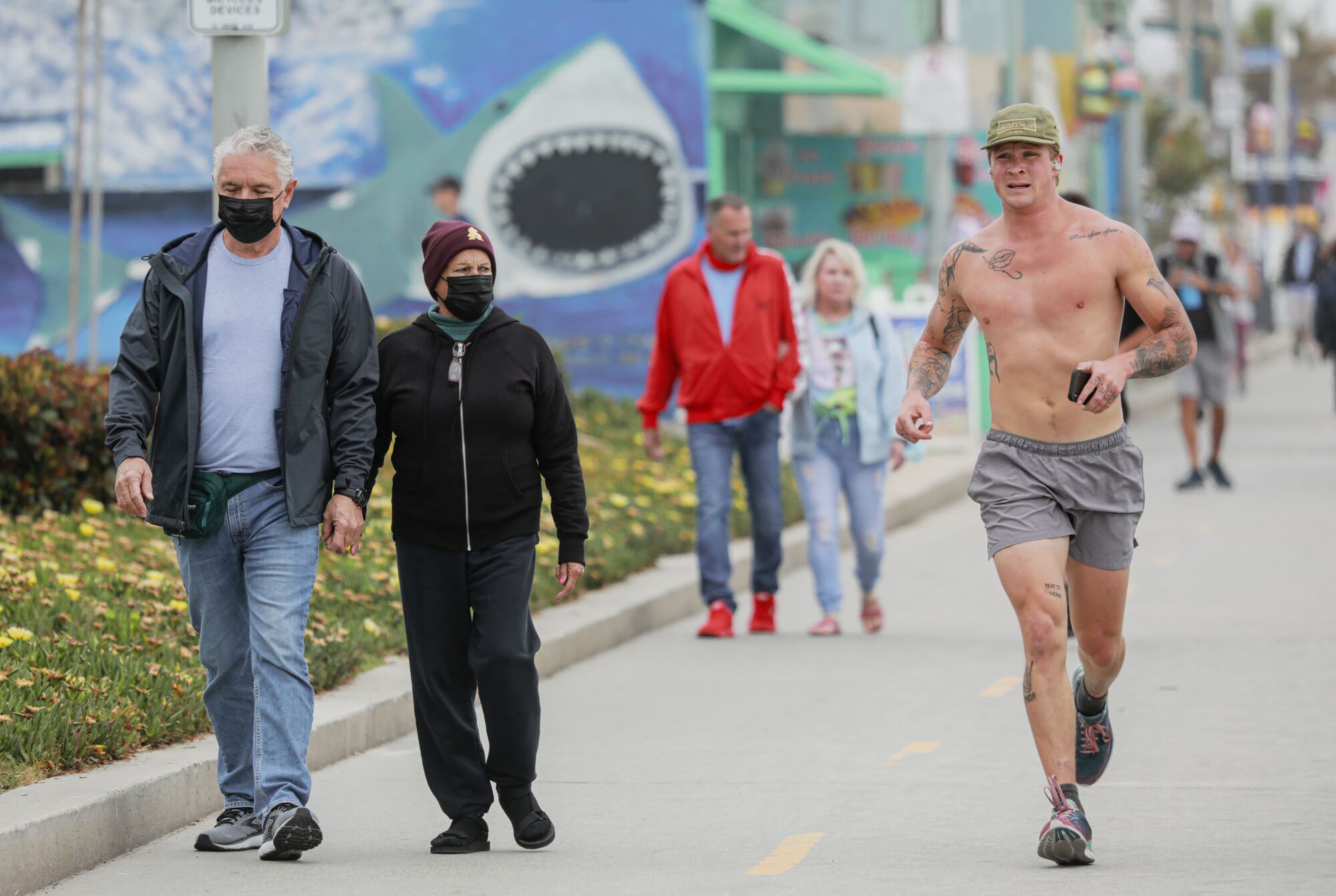 A mix of masked and unmasked people walk in Pacific Beach last month.