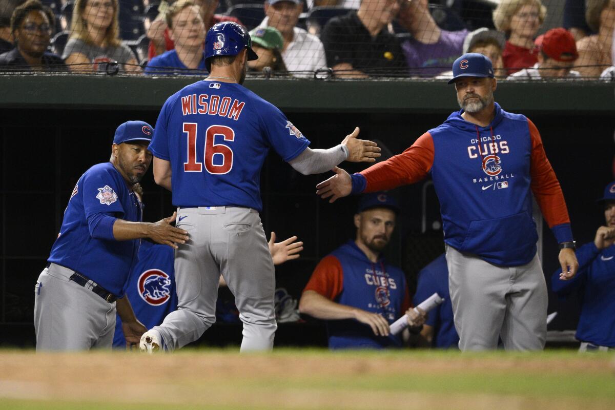Chicago Cubs' Patrick Wisdom (16) is greeted at the dugout after scoring on a single by Seiya Suzuki during the 11th inning of the team's baseball game against the Washington Nationals, Tuesday, Aug. 16, 2022, in Washington. The Cubs won 7-5 in 11 innings. (AP Photo/Nick Wass)