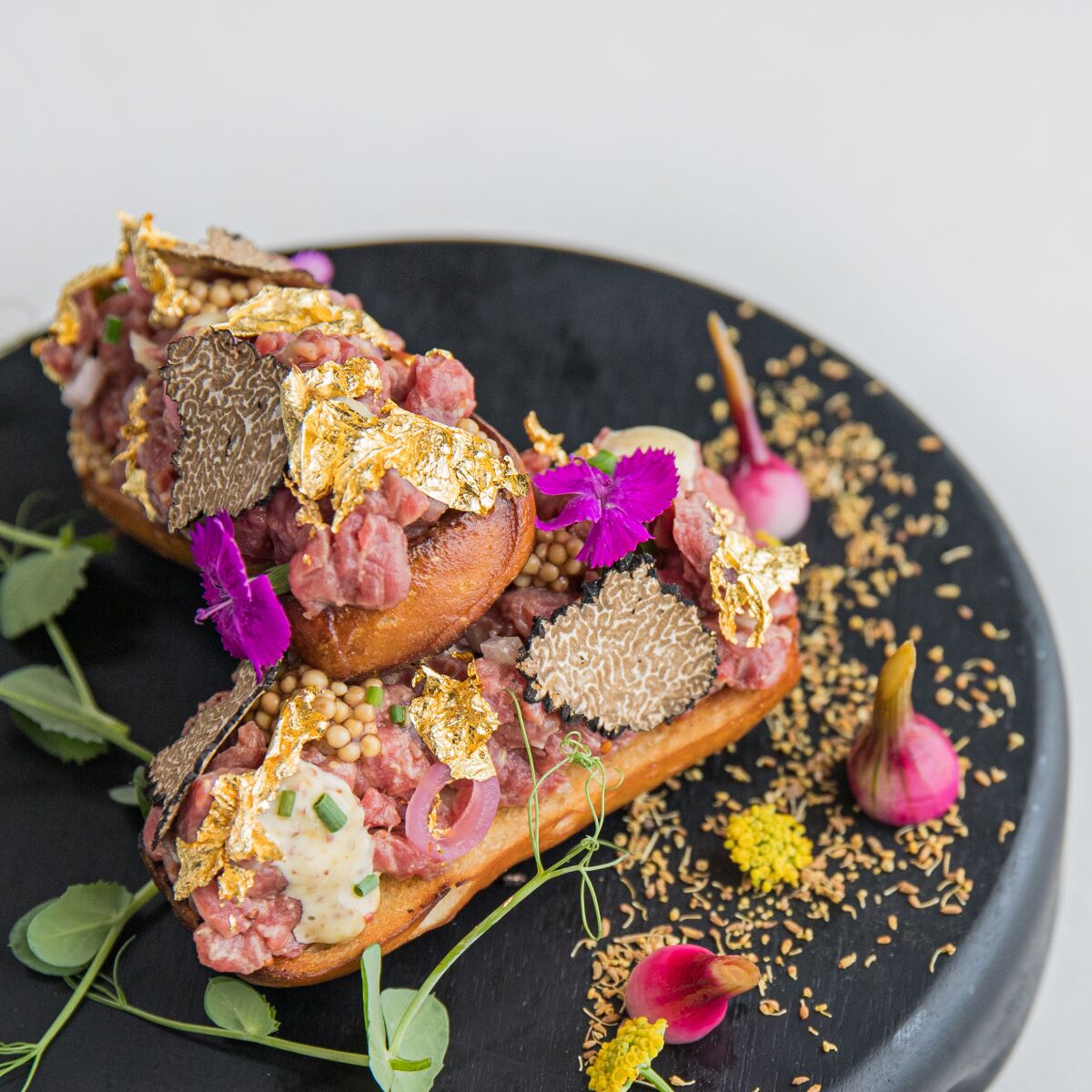 Beef tartare with black truffle and edible gold leaf on a baguette is on the menu at the Lounge at The Marine Room.