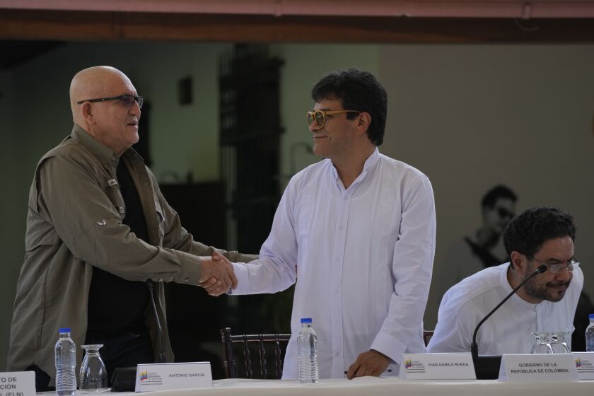 Antonio Garcia, of the Colombian guerrilla National Liberation Army (ELN), left, shakes hands with Ivan Danilo Rueda, High Commissioner for Peace on behalf of the Colombian government, after signing an agreement to resume peace talks, at the Casa Cultural Aquiles Nazoa in Caracas, Venezuela, Tuesday, Oct. 4, 2022. The agreement comes after more than four years of suspension, and will start in November. (AP Photo/Ariana Cubillos)