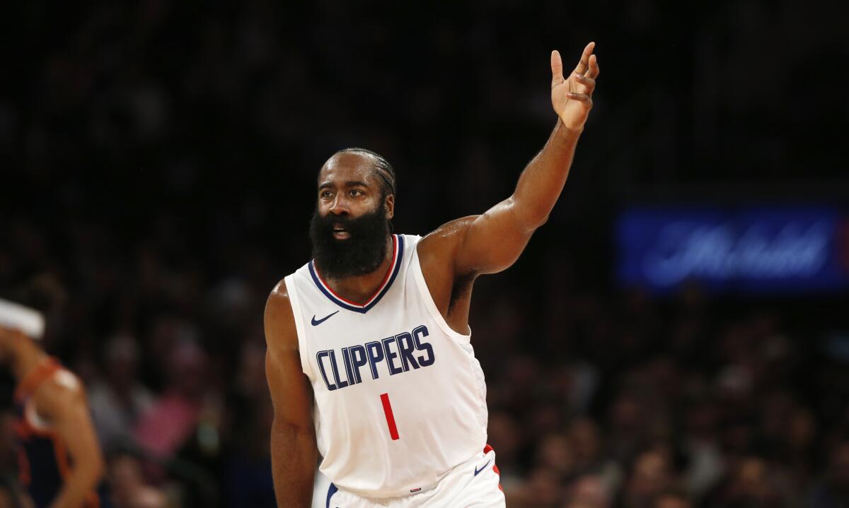 Clippers guard James Harden holds up three fingers after making a three-point shot.
