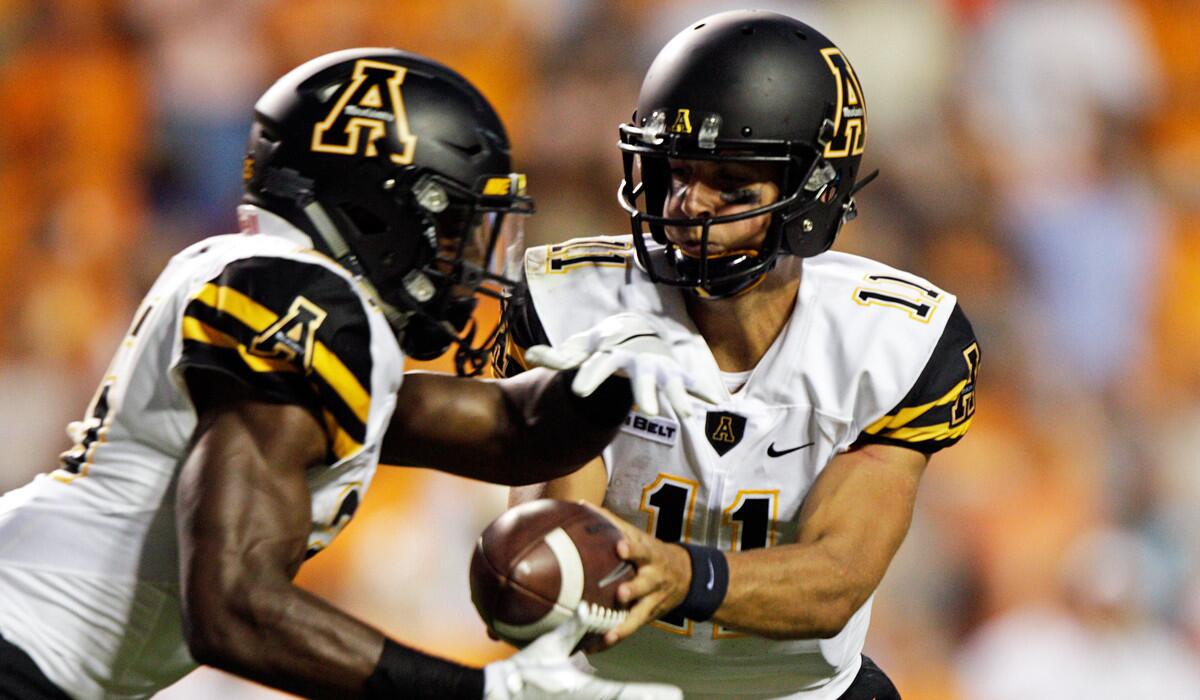 Appalachian State quarterback Taylor Lamb (11) hands the ball off to running back Jalin Moore during the first half against Tennessee on Thursday.