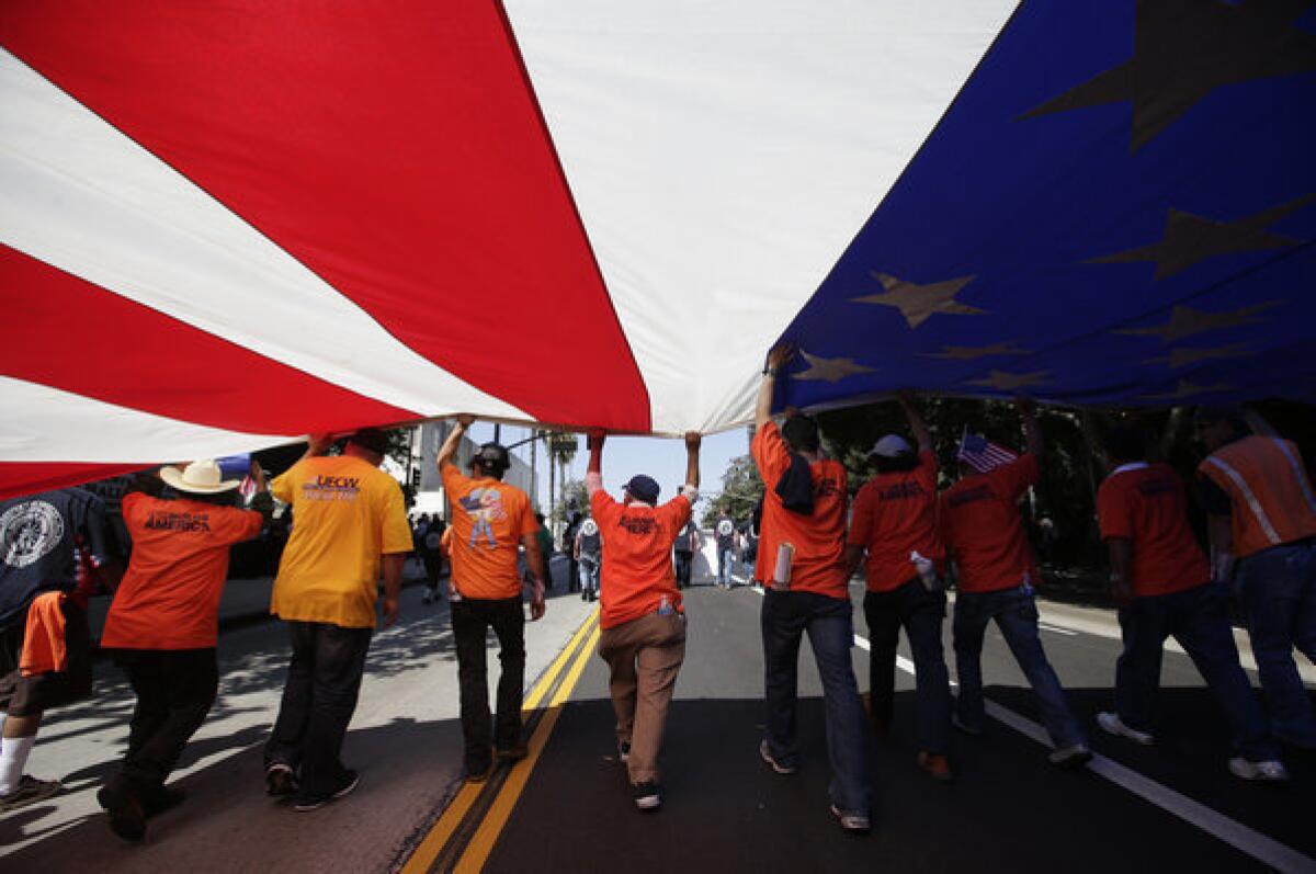 Union workers march along the street with a huge American flag during a May Day rally in Los Angeles.