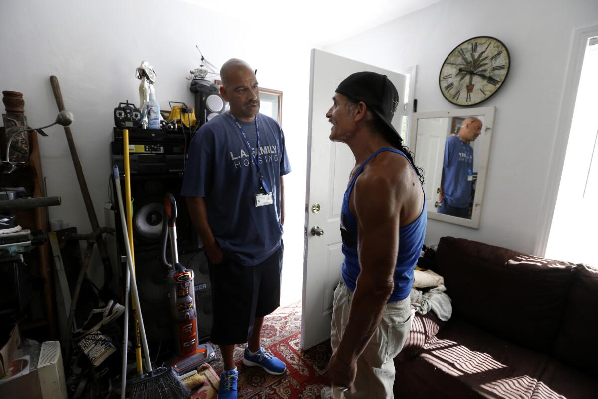 Eric Montoya, a L.A. Family Housings outreach worker, left, speaks with Dave Curry in his new apartment in Sunland. After a decade in the riverbed, Curry was ready to try living under a roof.