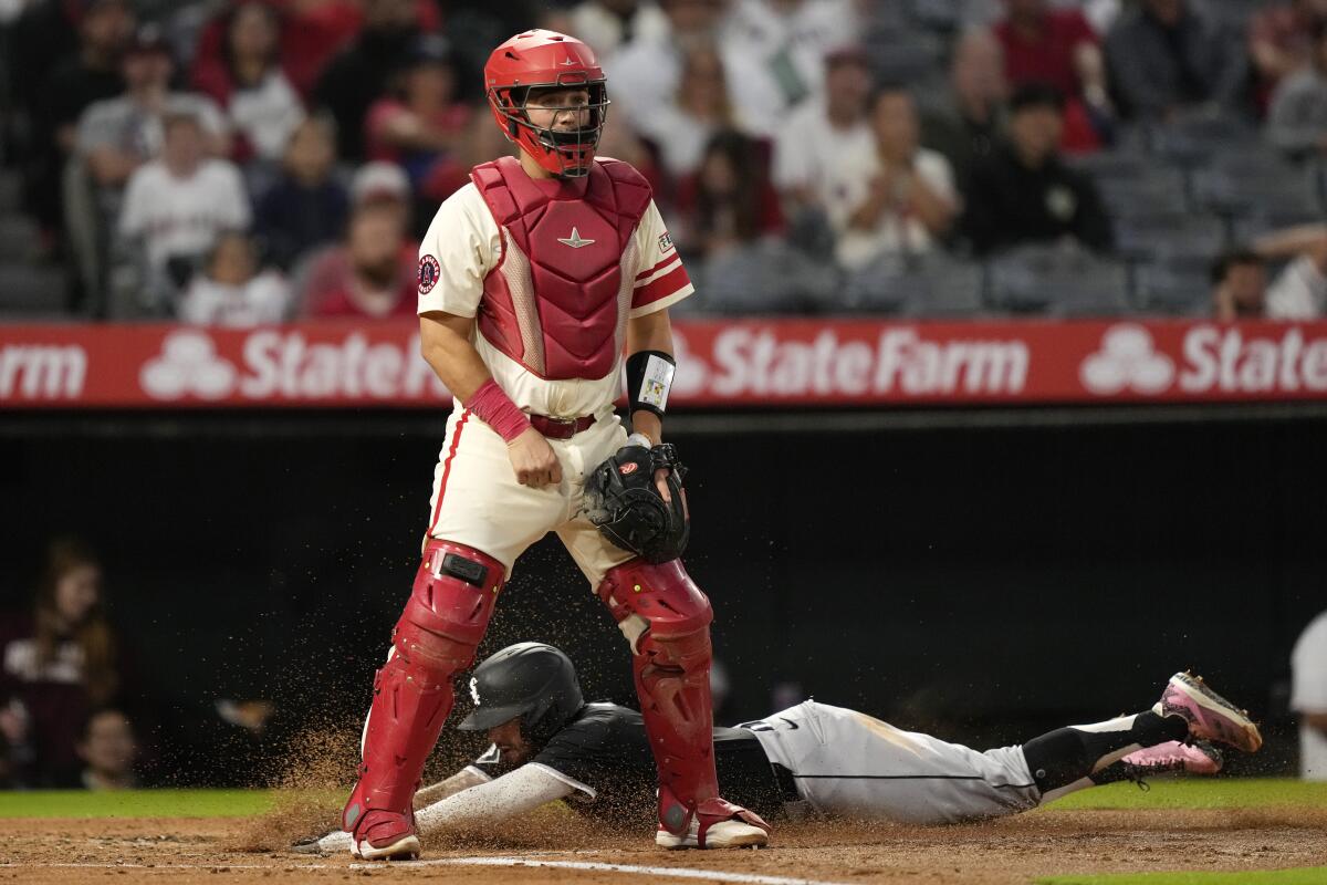 Chicago's Jacob Amaya, below, scores past Angels catcher Matt Thaiss at Angel Stadium.