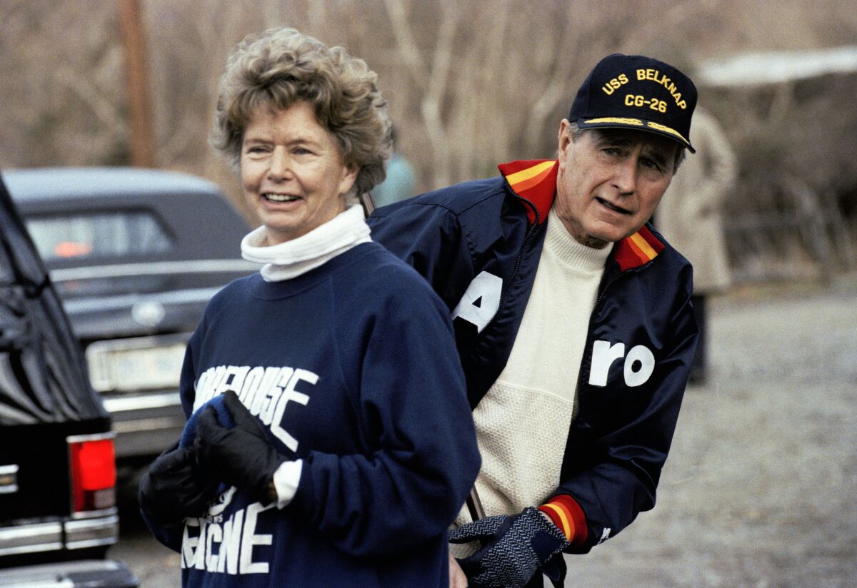 FILE — This Jan. 7, 1990, file photo shows President George H. W. Bush hiding behind his sister, Nancy Ellis, as he prepares for a jog along the C&O canal in the Georgetown section of Washington. A longtime Democrat who helped her Republican brother and nephew get elected president, died of complications of the coronavirus Sunday, Jan. 10, 2021, at an assisted living facility in Concord, Massachusetts. She was 94. (AP Photo/Marcy Nighswander, File)
