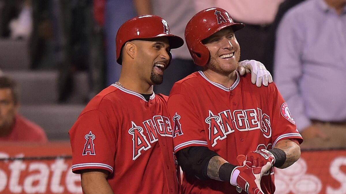 Angels teammates Albert Pujols, left, and Josh Hamilton share a laugh while a home run by Mike Trout was being reviewed during the fifth inning of the team's 4-1 win over the Oakland Athletics on Monday.