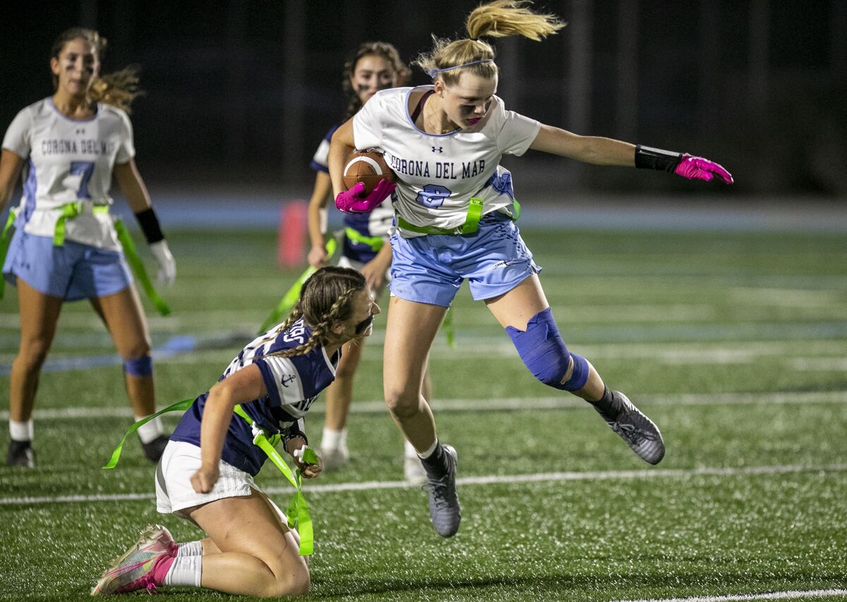 CdM's Alex Boserup leaps over Newport Harbor's Delaney Gahm after she pulls her flag during the Battle of the Bay game.