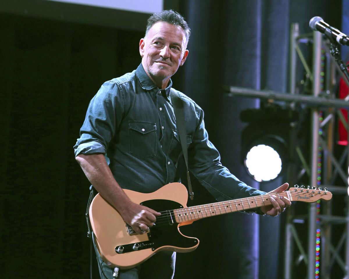Bruce Springsteen holding a guitar on a stage
