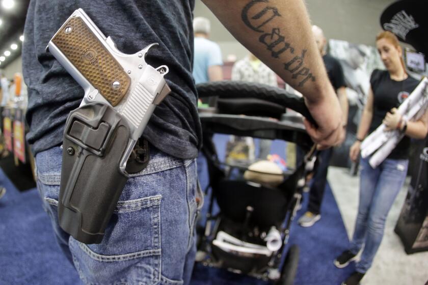 FILE - In this May 21, 2016, file photo, Donald Carder wears his handgun in a holster as he pushes his son, Waylon, in a stroller at the National Rifle Association convention in Louisville, Ky. Attendees at the convention are permitted to carry firearms under Kentucky's open carry law. (AP Photo/Mark Humphrey, File)