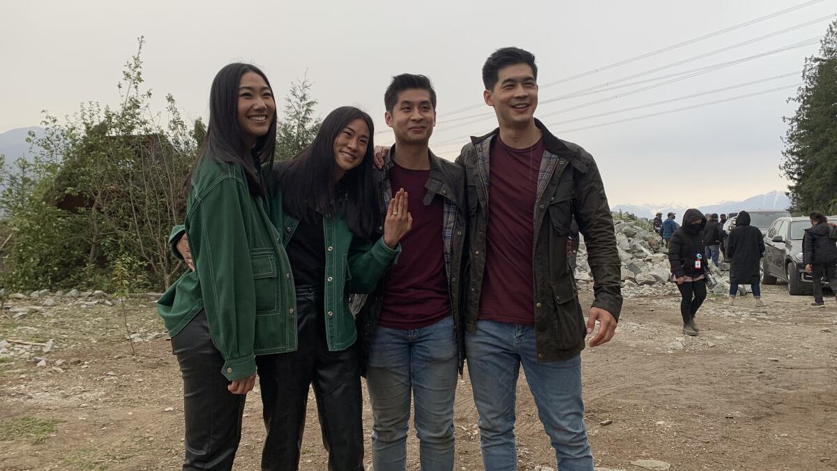 Two women dressed in identical outfits stand with two men dressed in identical outfits.