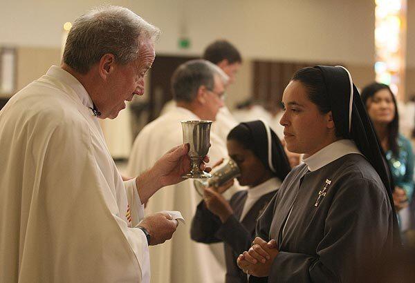 Father Christopher Smith distributes Holy Communion during the ordination to the priesthood of four men at St. Columban Church in Garden Grove. Smith will take the top post at the new Christ Cathedral.