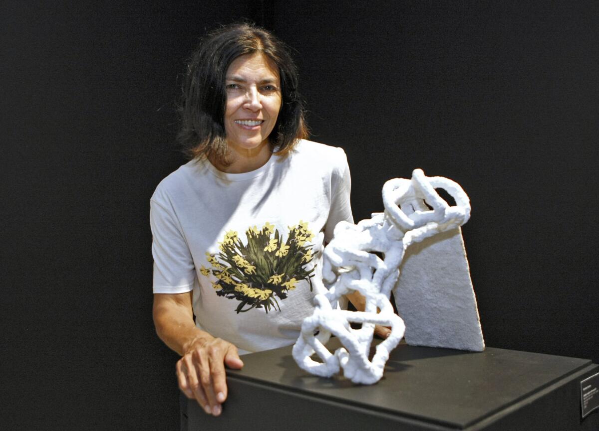 Mixed-media artist Nicholette Kominos in front of her untitled sculpture, from the current exhibit Gravitas at the Brand Library & Art Center.