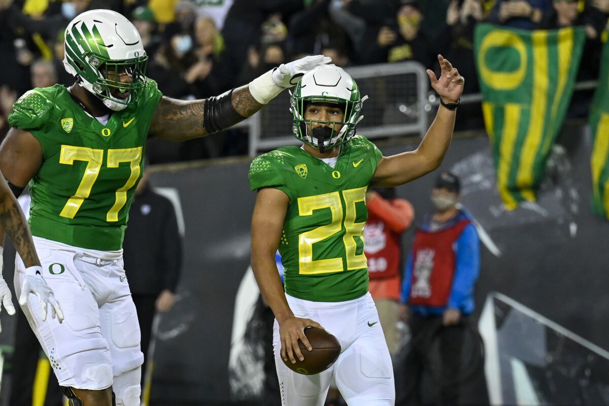 Oregon running back Travis Dye (26) celebrates his touchdown against Washington St with offensive lineman George Moore (77) during the first quarter of an NCAA college football game Saturday, Nov. 13, 2021, in Eugene, Ore. (AP Photo/Andy Nelson)