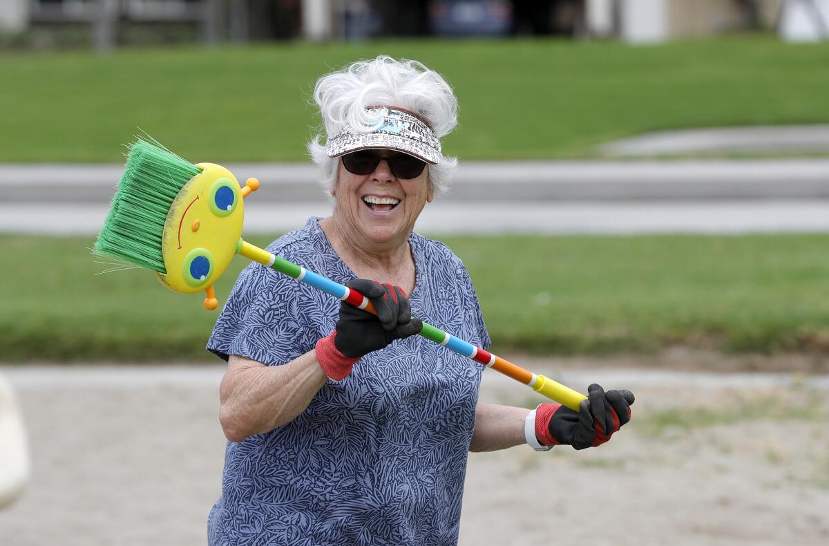 Maureen Farsadi pauses from clearing overgrown grass from the playground at Golden View Park in Huntington Beach on Monday.