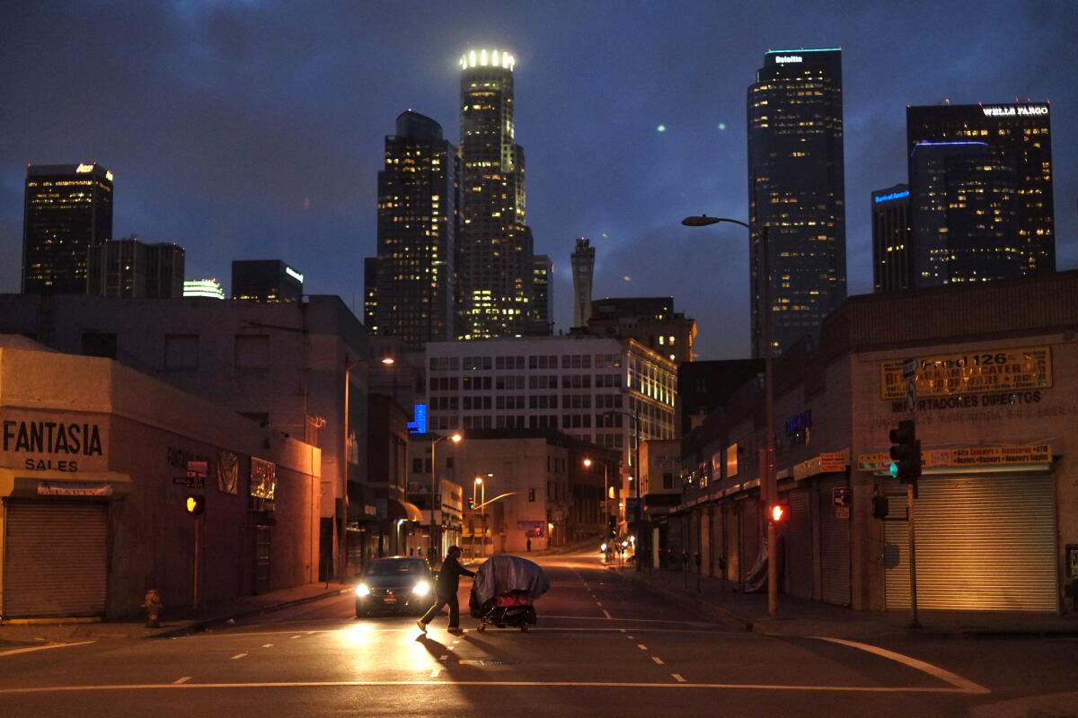 A homeless resident pushes a cart along a downtown Los Angeles street.