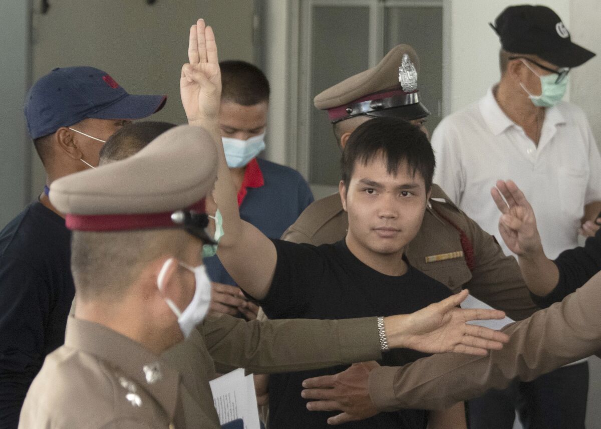 Thai activist Tattep Ruangprapaikitseree gives a three-finger salute as he leaves a police station in Bangkok. 