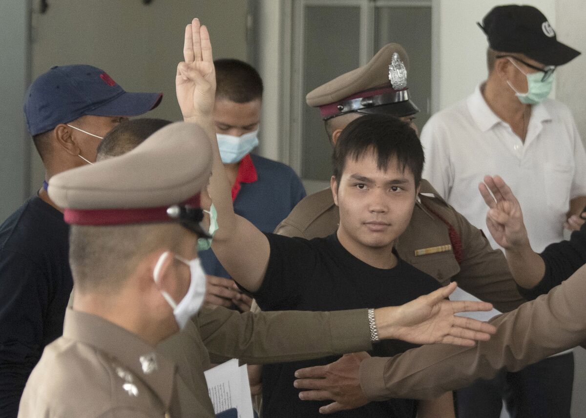 Thai activist Tattep Ruangprapaikitseree gives a three-finger salute as he leaves a police station in Bangkok.
