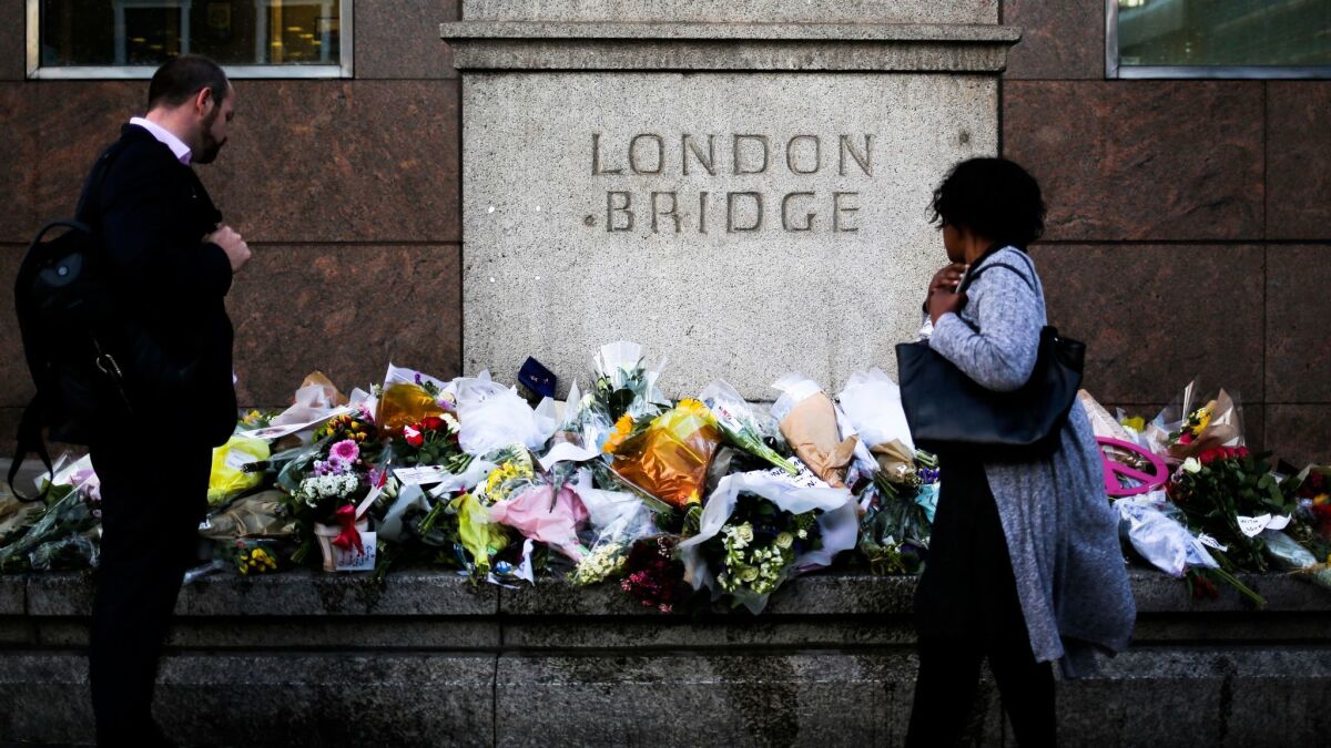 On Tuesday, passersby survey the floral tributes placed at London Bridge in honor of the victims of Saturday's attack.