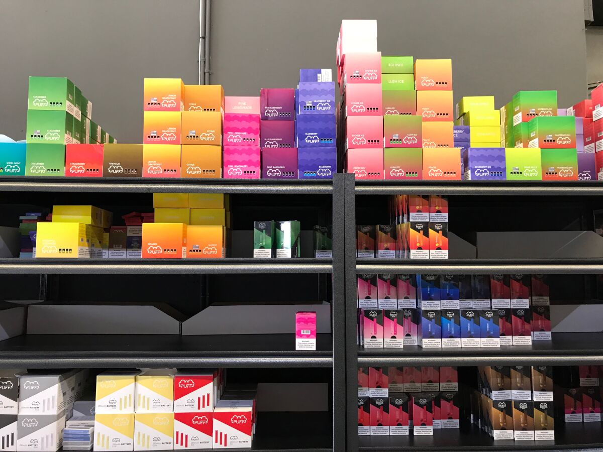 Flavored vaping products in colorful boxes on a shelf.