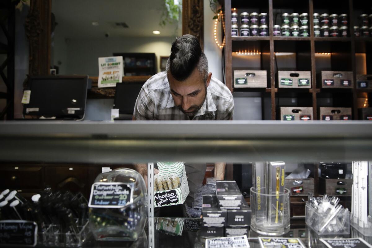 Jerred Kiloh, owner of the Higher Path medical marijuana dispensary, stocks shelves with cannabis products in Los Angeles.