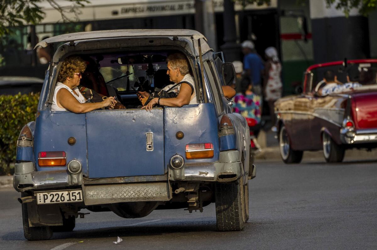 ARCHIVO - Mujeres viajan en la parte trasera de un taxi colectivo en La Habana, Cuba, 