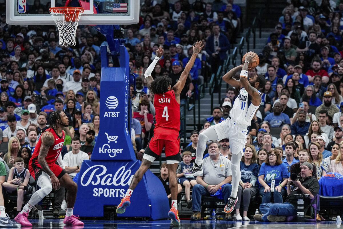 This handout photo provided by the Dallas Mavericks shows Dallas Mavericks guard Kyrie Irving (11) shooting against Houston Rockets defenders Jalen Green (4) and Cam Whitmore (7) during the first half of an NBA basketball game Sunday, April 7, 2024 in Dallas. (Dallas Mavericks via AP)