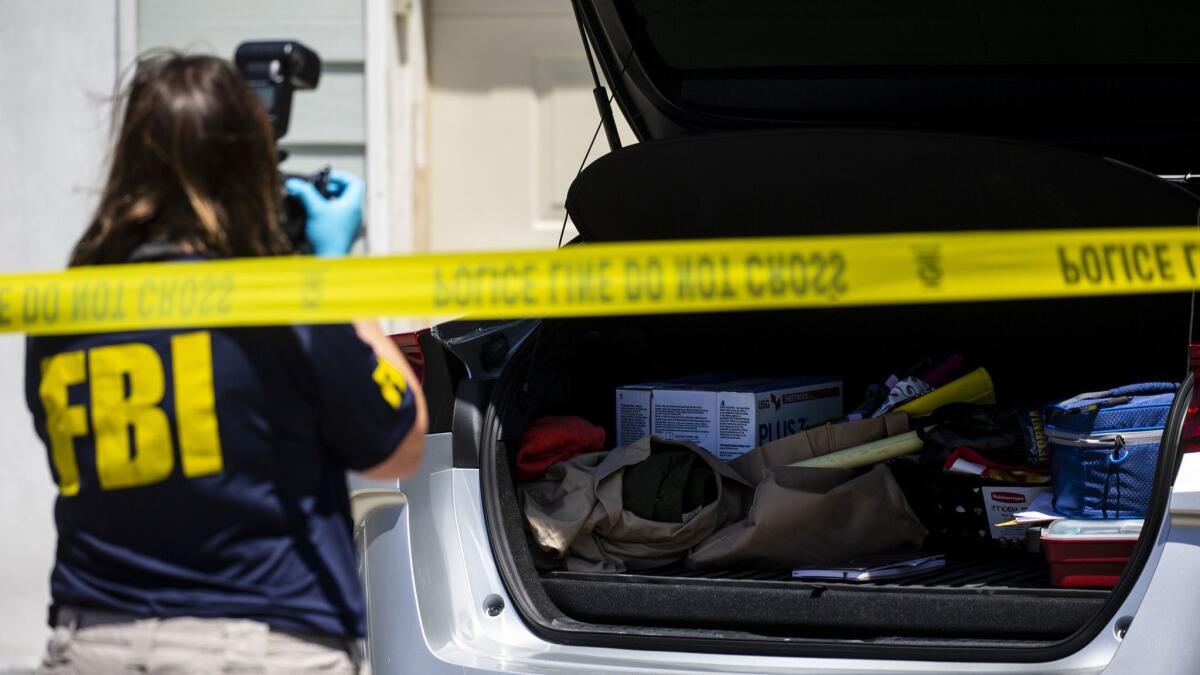 Law enforcement officials inspect a car last week as part of an investigation into an explosion that ripped through an Aliso Viejo day spa on Tuesday, killing the owner and injuring two customers.