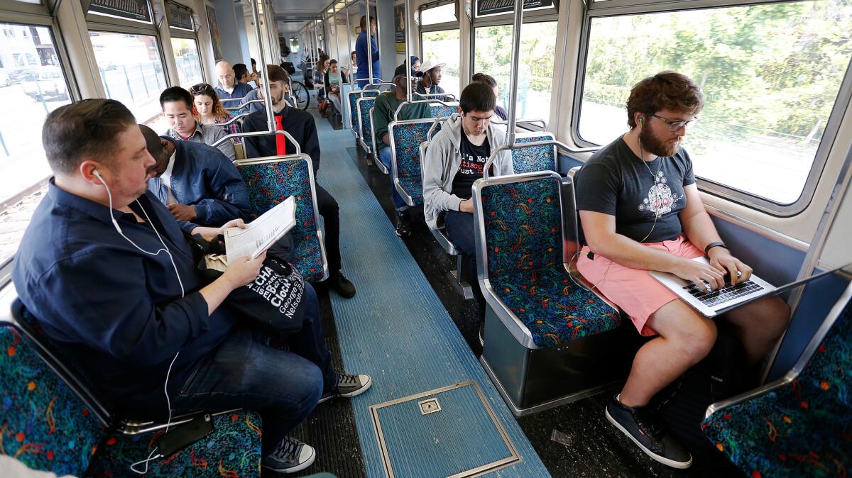 Josiah Davis, right, rides the new Expo Line to his tech job in Santa Monica. Until this week, he faced commutes of up to three hours each way from his home in Long Beach.